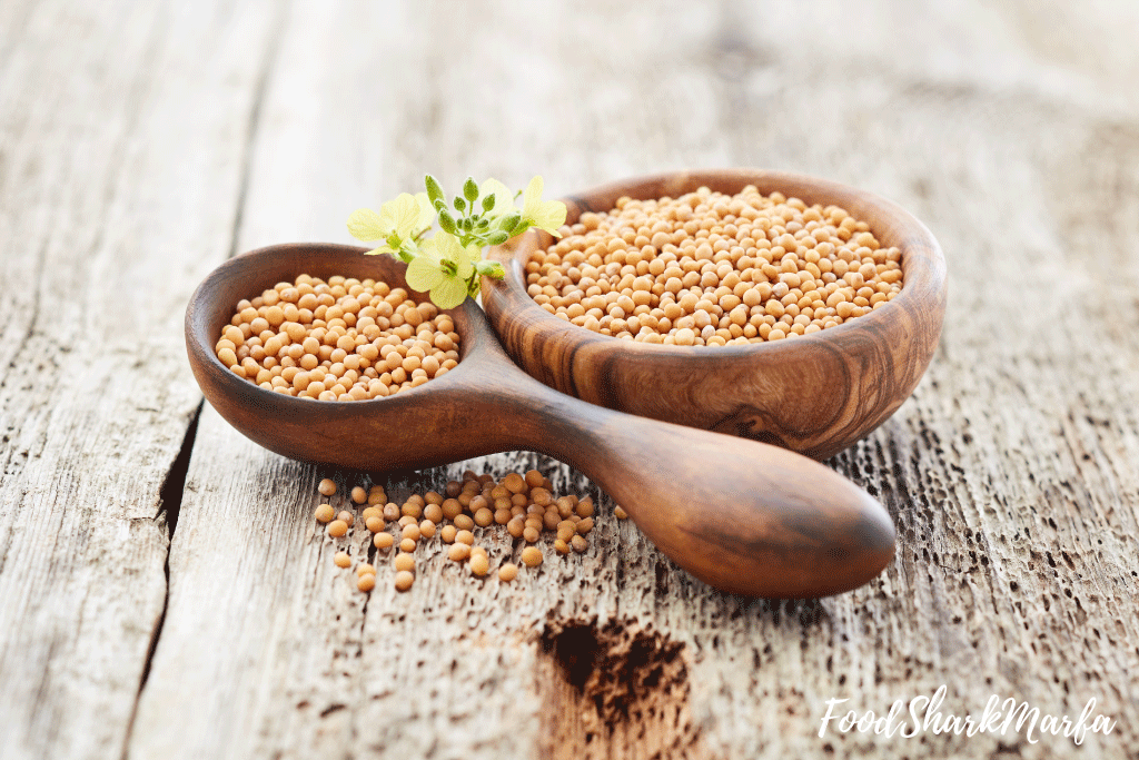 Mustard-seeds-with-flowers-on-wooden-background Mustard seeds with flowers on wooden background